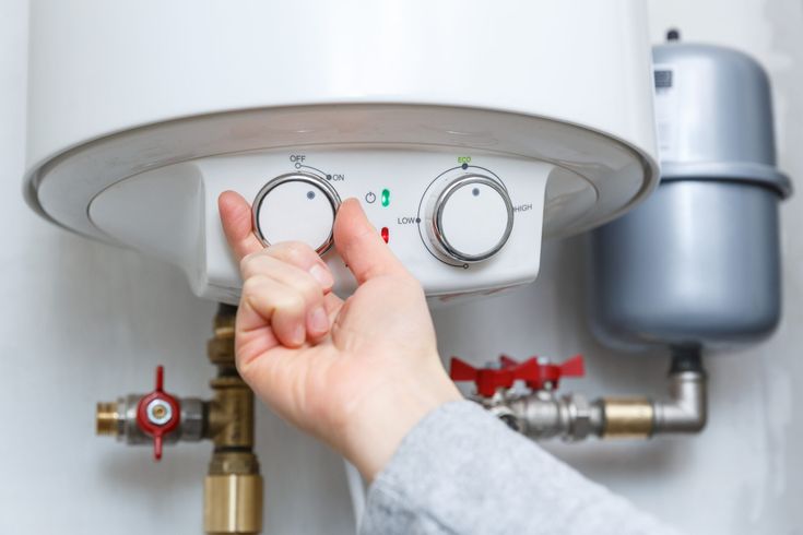 drain-cleaning female hand turning on electric water heater (boiler).