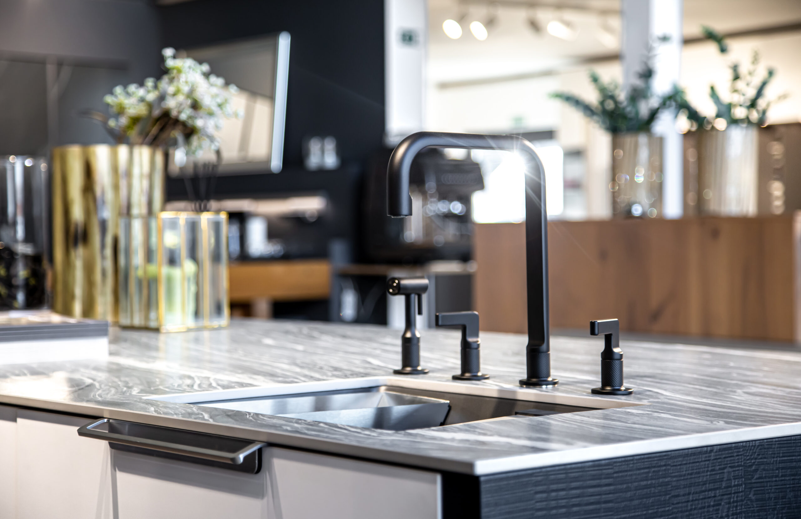 Kitchen Plumbing Services black faucet with a steel sink in a stylish modern kitchen.