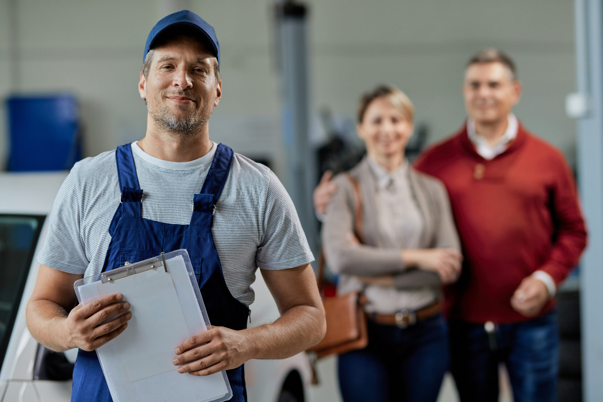 portrait of happy car mechanic with his customers in the backgro